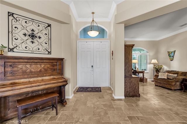 foyer entrance featuring crown molding, stone tile floors, and baseboards