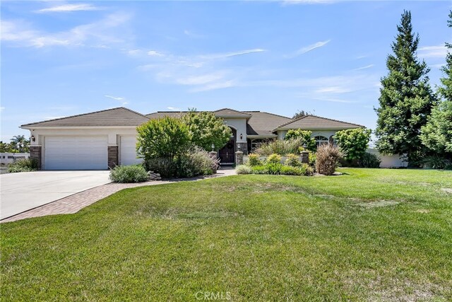 view of front facade featuring concrete driveway, an attached garage, a front yard, a tile roof, and stucco siding