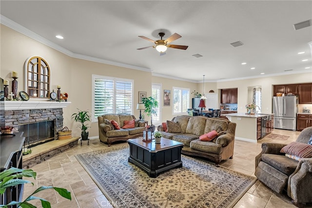 living room with stone tile flooring, a ceiling fan, crown molding, a fireplace, and recessed lighting