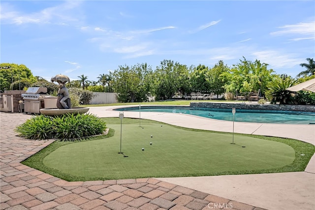 outdoor pool featuring an area to practice putting, a patio, and an outdoor kitchen
