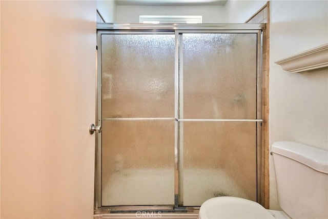 bathroom featuring toilet and an enclosed shower