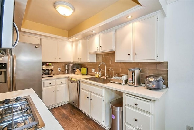kitchen featuring appliances with stainless steel finishes, a sink, light countertops, and tasteful backsplash