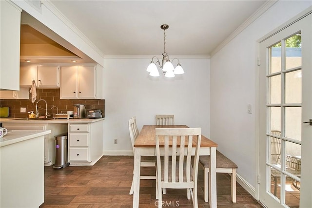 dining room with a chandelier, dark wood-type flooring, ornamental molding, and baseboards