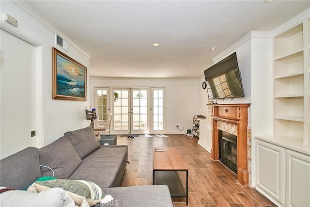 living room featuring a fireplace, wood finished floors, crown molding, baseboards, and built in features