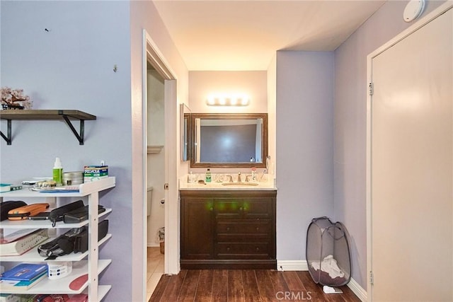 bathroom with wood finished floors, vanity, toilet, and baseboards