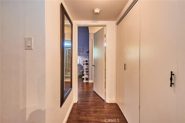 hallway featuring dark wood finished floors and baseboards