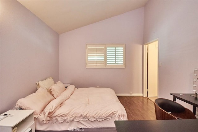 bedroom with lofted ceiling, wood finished floors, and baseboards