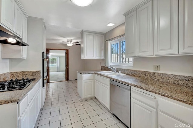 kitchen featuring appliances with stainless steel finishes, a sink, a ceiling fan, light tile patterned floors, and white cabinets