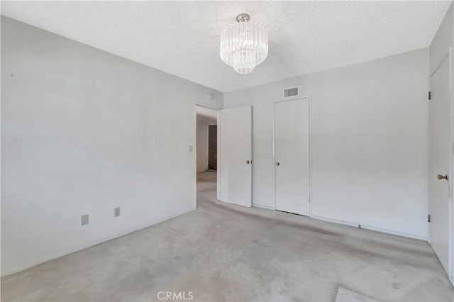 unfurnished bedroom with carpet floors, a chandelier, a textured ceiling, and a closet