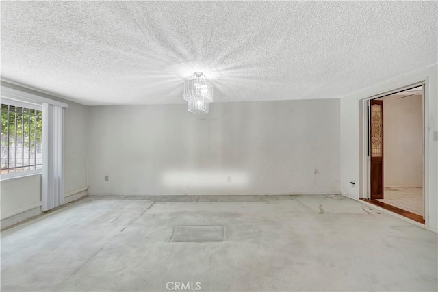 spare room featuring a textured ceiling, concrete floors, and baseboards