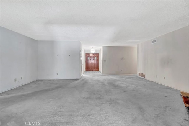 empty room featuring a textured ceiling, light carpet, a chandelier, and baseboards