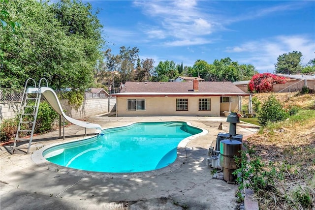 view of swimming pool featuring a water slide, a patio, and a fenced backyard