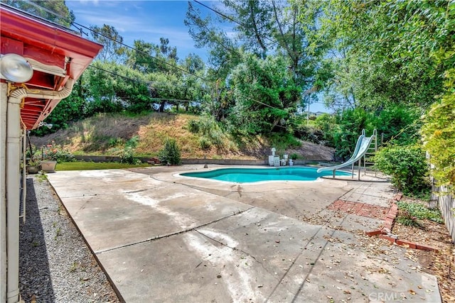 outdoor pool with a water slide and a patio area