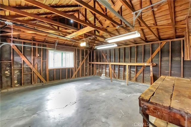 miscellaneous room featuring unfinished concrete floors and lofted ceiling