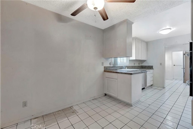 kitchen with a ceiling fan, a textured ceiling, dark countertops, white cabinets, and baseboards