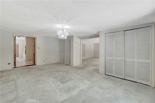 unfurnished bedroom with carpet flooring, a chandelier, a closet, and a textured ceiling