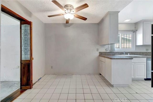 kitchen featuring a textured ceiling, a ceiling fan, dark countertops, white cabinets, and a sink