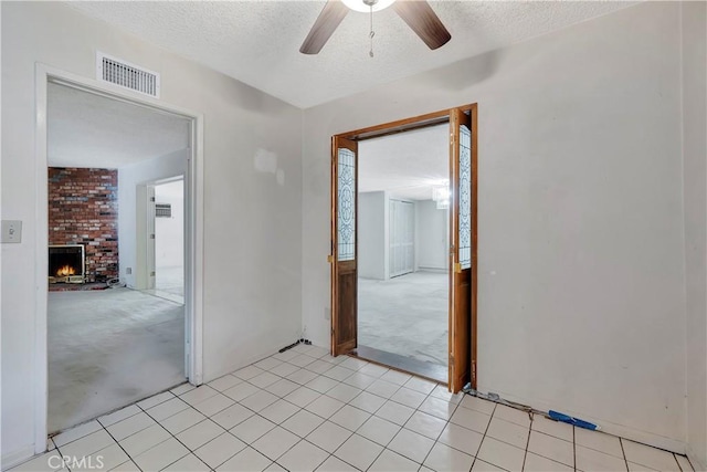 unfurnished room featuring light carpet, a ceiling fan, a textured ceiling, and a brick fireplace