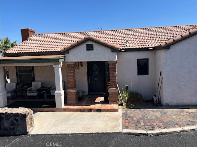 525 S L St, Needles, CA 92363 - view of front of home featuring stucco siding, a chimney, a tile roof, and a porch
