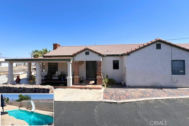 525 S L St, Needles, CA 92363 - view of front of house featuring a tiled roof, stucco siding, a chimney, and covered porch