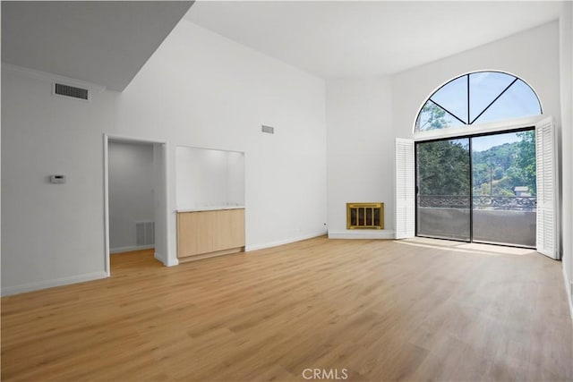 14844 Dickens St Unit 306, Sherman Oaks, CA 91403 - unfurnished living room featuring high vaulted ceiling, light wood-type flooring, baseboards, and a glass covered fireplace