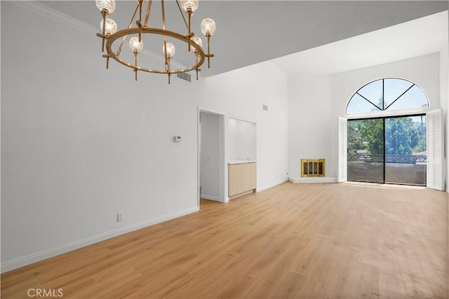 14844 Dickens St Unit 306, Sherman Oaks, CA 91403 - unfurnished living room with a chandelier, baseboards, light wood-style floors, a towering ceiling, and crown molding