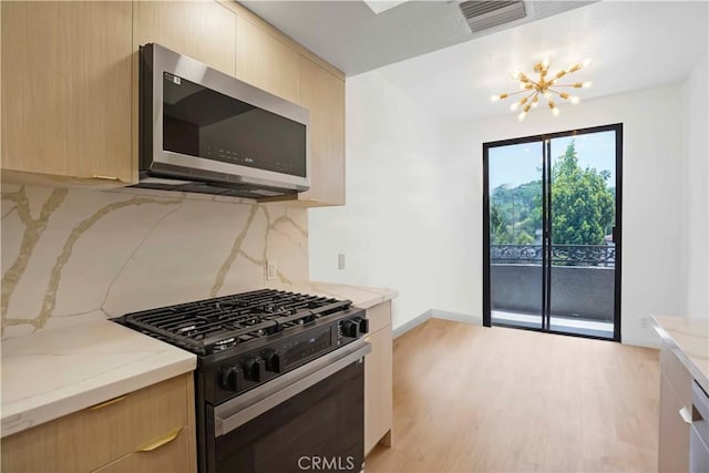 14844 Dickens St Unit 306, Sherman Oaks, CA 91403 - kitchen featuring black range with gas stovetop, stainless steel microwave, light brown cabinets, a chandelier, and decorative backsplash