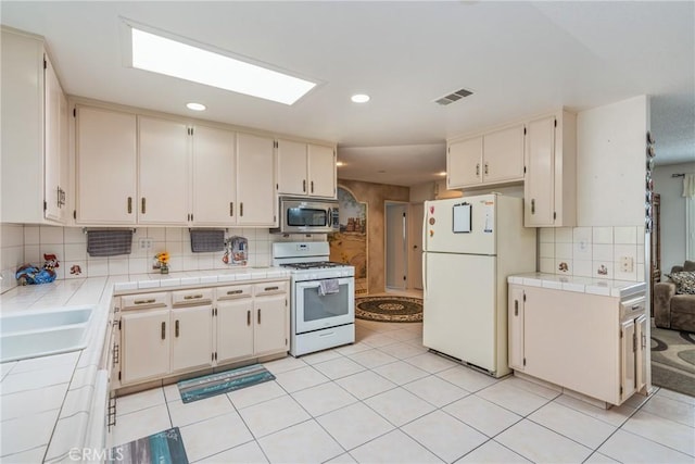 1561 W Wesley Pl, Hemet, CA 92543 - kitchen with white appliances, tile countertops, decorative backsplash, cream cabinets, and recessed lighting
