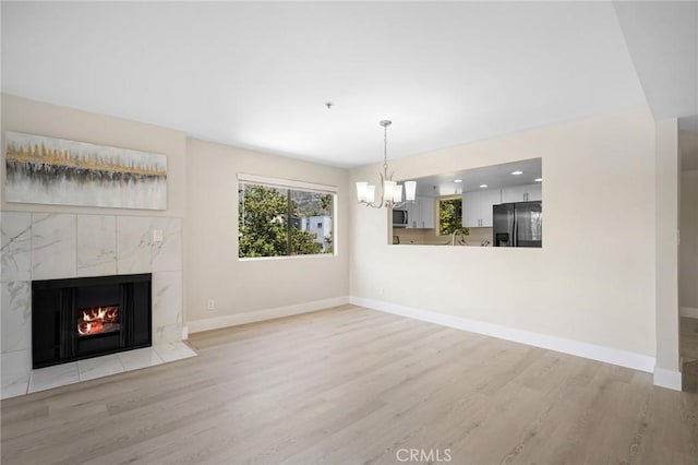 450 W Dryden St Unit 201, Glendale, CA 91202 - unfurnished living room with light wood finished floors, a chandelier, a high end fireplace, and baseboards