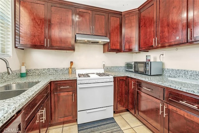 5915 Weedpatch, Bakersfield, CA 93307 - kitchen featuring under cabinet range hood, white gas range, black microwave, reddish brown cabinets, and light tile patterned flooring