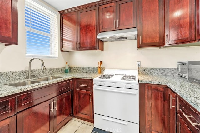 5915 Weedpatch, Bakersfield, CA 93307 - kitchen featuring white gas range, under cabinet range hood, a sink, reddish brown cabinets, and light stone countertops