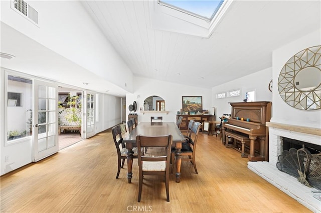 317 Walnut St, Costa Mesa, CA 92627 - dining room featuring a fireplace, a skylight, light wood-style floors, and vaulted ceiling
