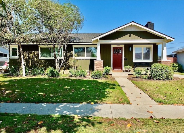 1820 Carfax Ave, Long Beach, CA 90815 - view of front facade with board and batten siding, a front yard, a chimney, and a porch
