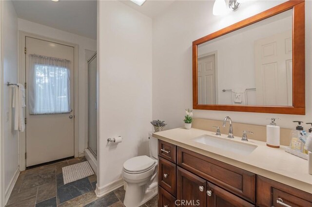 435 S Estate Dr, Orange, CA 92869 - bathroom with baseboards, toilet, stone finish flooring, a shower with door, and vanity