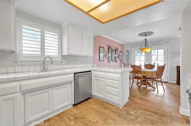 kitchen with dishwasher, a sink, white cabinets, a peninsula, and tile countertops