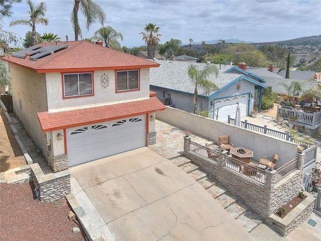 view of front of house with stucco siding, roof mounted solar panels, a garage, and concrete driveway