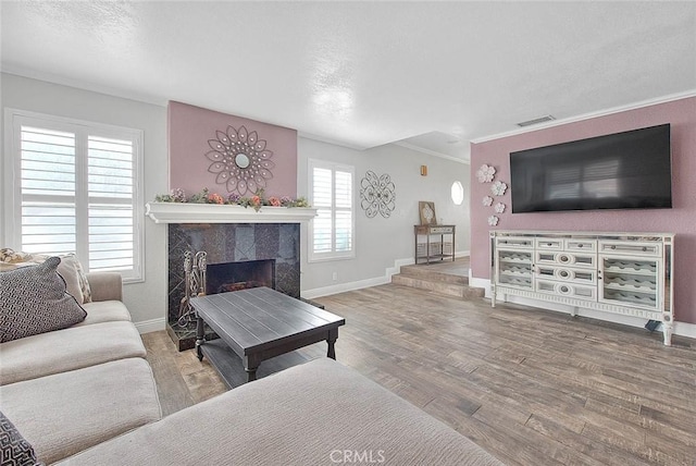 living area featuring wood finished floors, baseboards, a high end fireplace, crown molding, and a textured ceiling