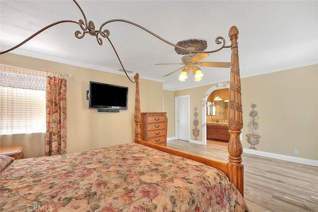 bedroom with wood finished floors, multiple windows, crown molding, baseboards, and ceiling fan