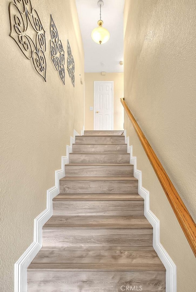 stairway with wood finished floors and a textured wall