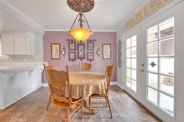 dining room featuring light wood-style floors, crown molding, and baseboards