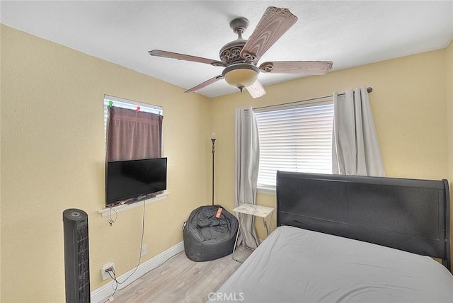 bedroom featuring wood finished floors, baseboards, and a ceiling fan