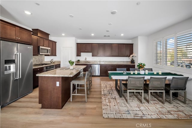 8713 Roving Pl, Chino, CA 91708 - kitchen with appliances with stainless steel finishes, a center island, dark brown cabinetry, light wood-style floors, and recessed lighting