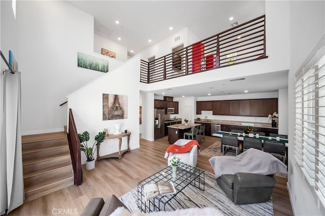 8713 Roving Pl, Chino, CA 91708 - living area featuring stairs, a high ceiling, light wood-style flooring, baseboards, and recessed lighting