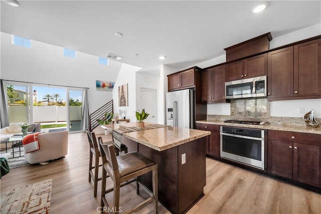 8713 Roving Pl, Chino, CA 91708 - kitchen featuring stainless steel appliances, light wood-style flooring, a kitchen island, light stone counters, and recessed lighting