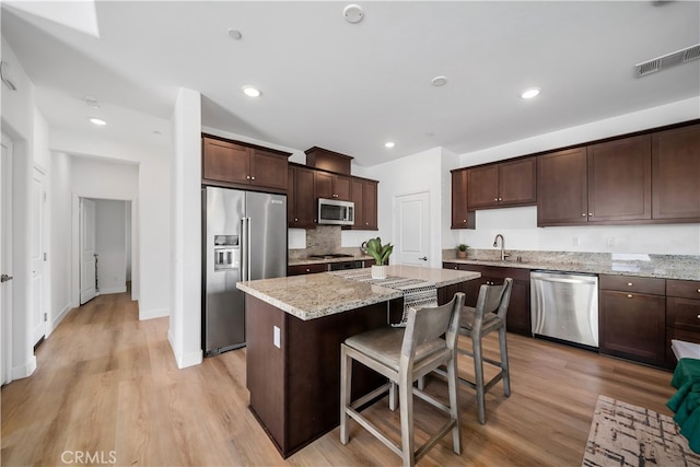 8713 Roving Pl, Chino, CA 91708 - kitchen with stainless steel appliances, a center island, dark brown cabinets, a breakfast bar area, and recessed lighting