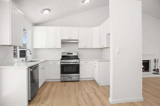 4888 Northerly St, Oceanside, CA 92056 - kitchen featuring appliances with stainless steel finishes, under cabinet range hood, a sink, vaulted ceiling, and light wood-style flooring