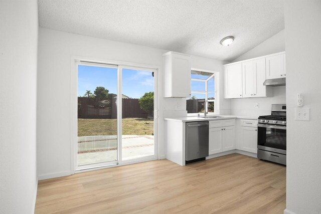 4888 Northerly St, Oceanside, CA 92056 - kitchen with stainless steel appliances, under cabinet range hood, a textured ceiling, white cabinets, and light wood-style floors