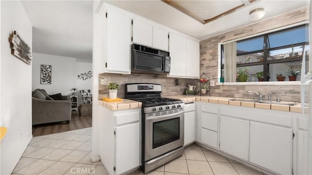 3458 Santa Barbara Ct, Palmdale, CA 93550 - kitchen with black microwave, stainless steel range with gas cooktop, a sink, tasteful backsplash, and white cabinets