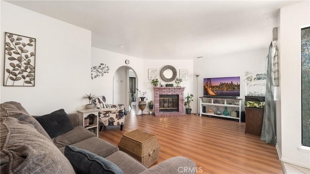 3458 Santa Barbara Ct, Palmdale, CA 93550 - living room with wood finished floors, arched walkways, and a brick fireplace