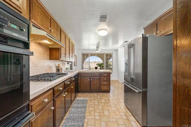 1466 Pacific Ave, Norco, CA 92860 - kitchen featuring black appliances, tile countertops, a peninsula, decorative backsplash, and under cabinet range hood